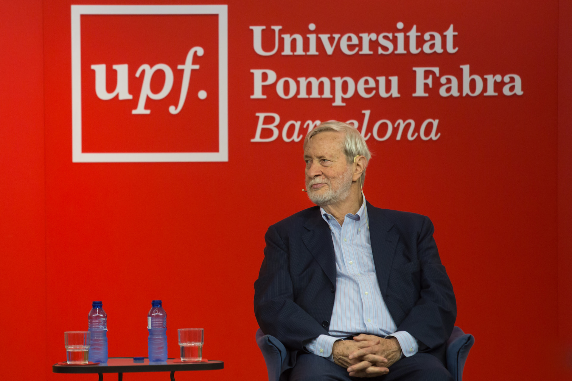 Gianni Vattimo on stage at Universitat Pompeu Fabra, before the red UPF backdrop